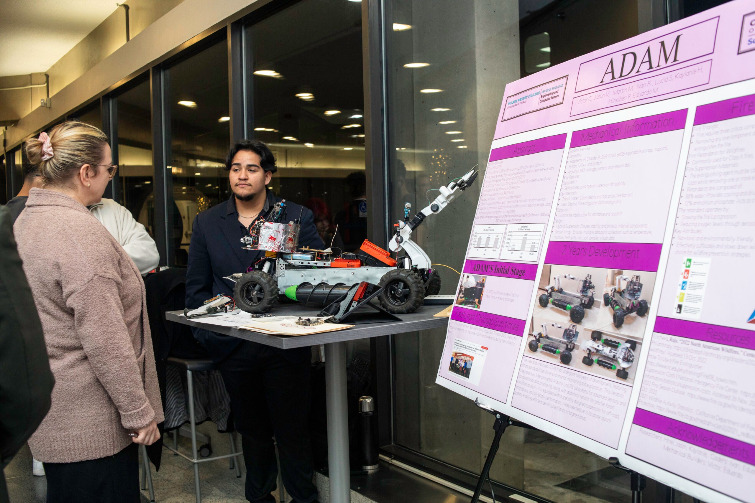 Student showcases a poster and robot.